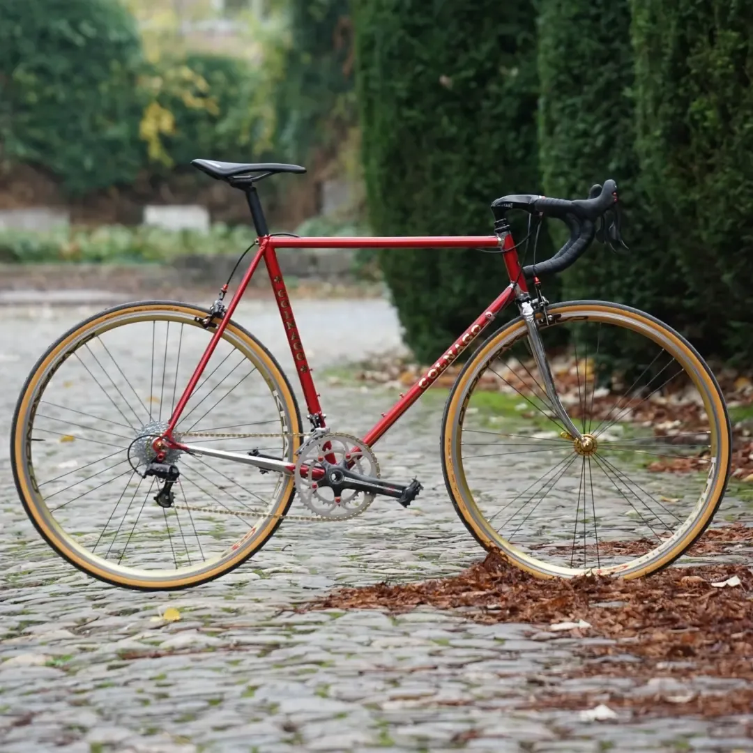 Rode Colnago stalen koersfiets op kasseien in de herfst